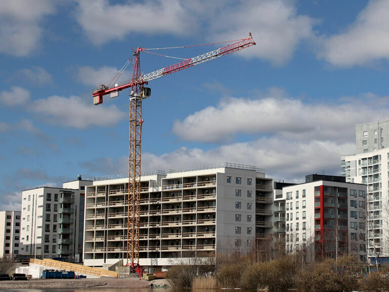 A modern apartment house is being built in urban, densely built